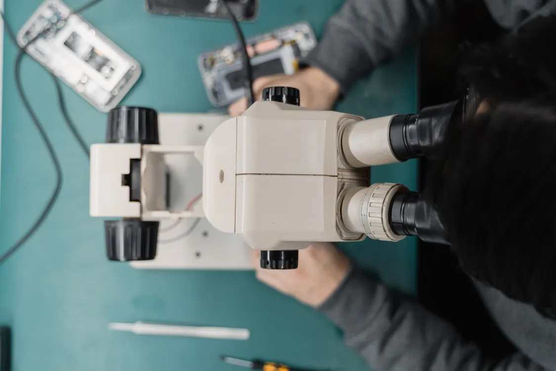 Nahaufnahme eines Mikroskops bei der präzisen Reparatur eines Smartphones.